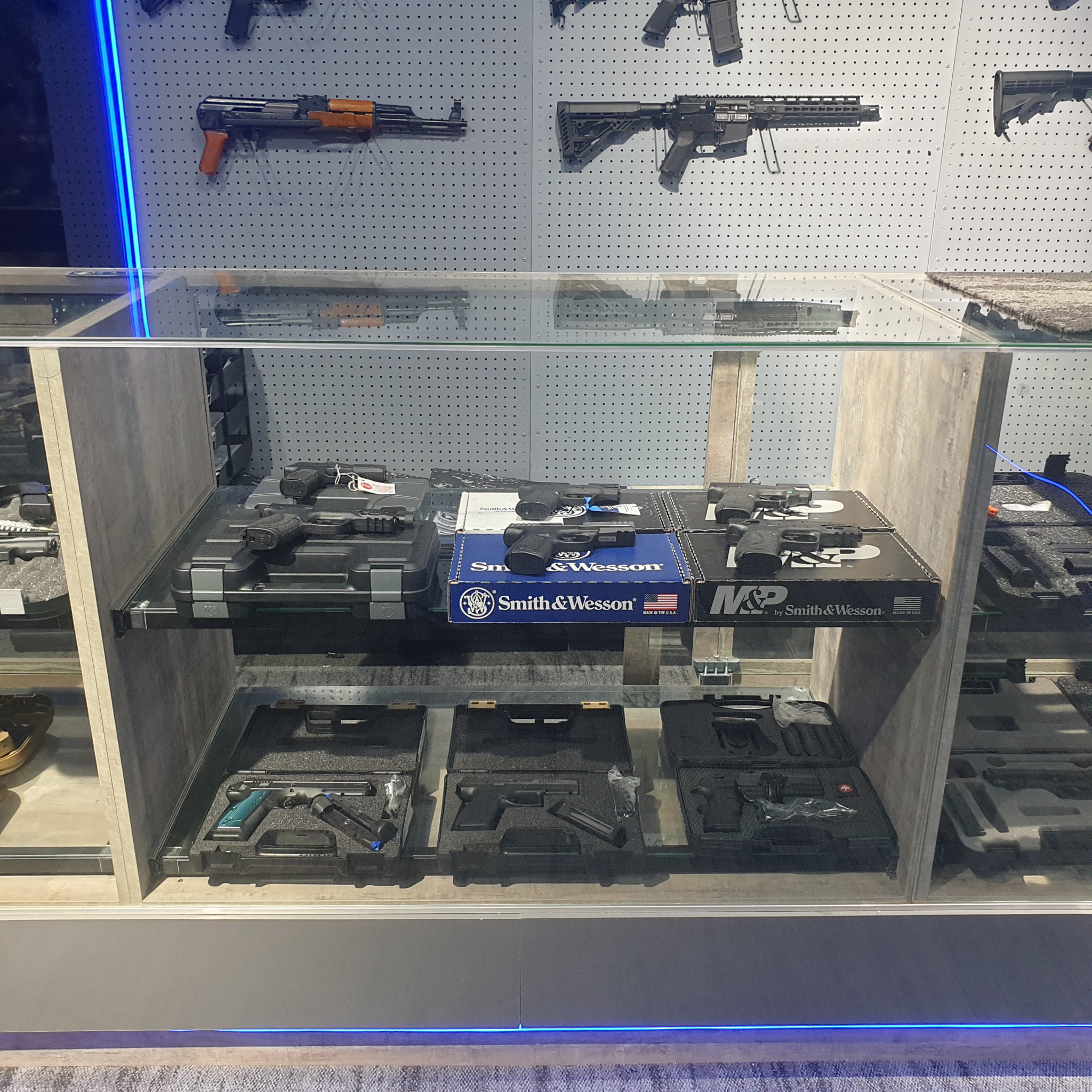 Pistol counter with Smith & Wesson and M&P boxes below the rifle display wall