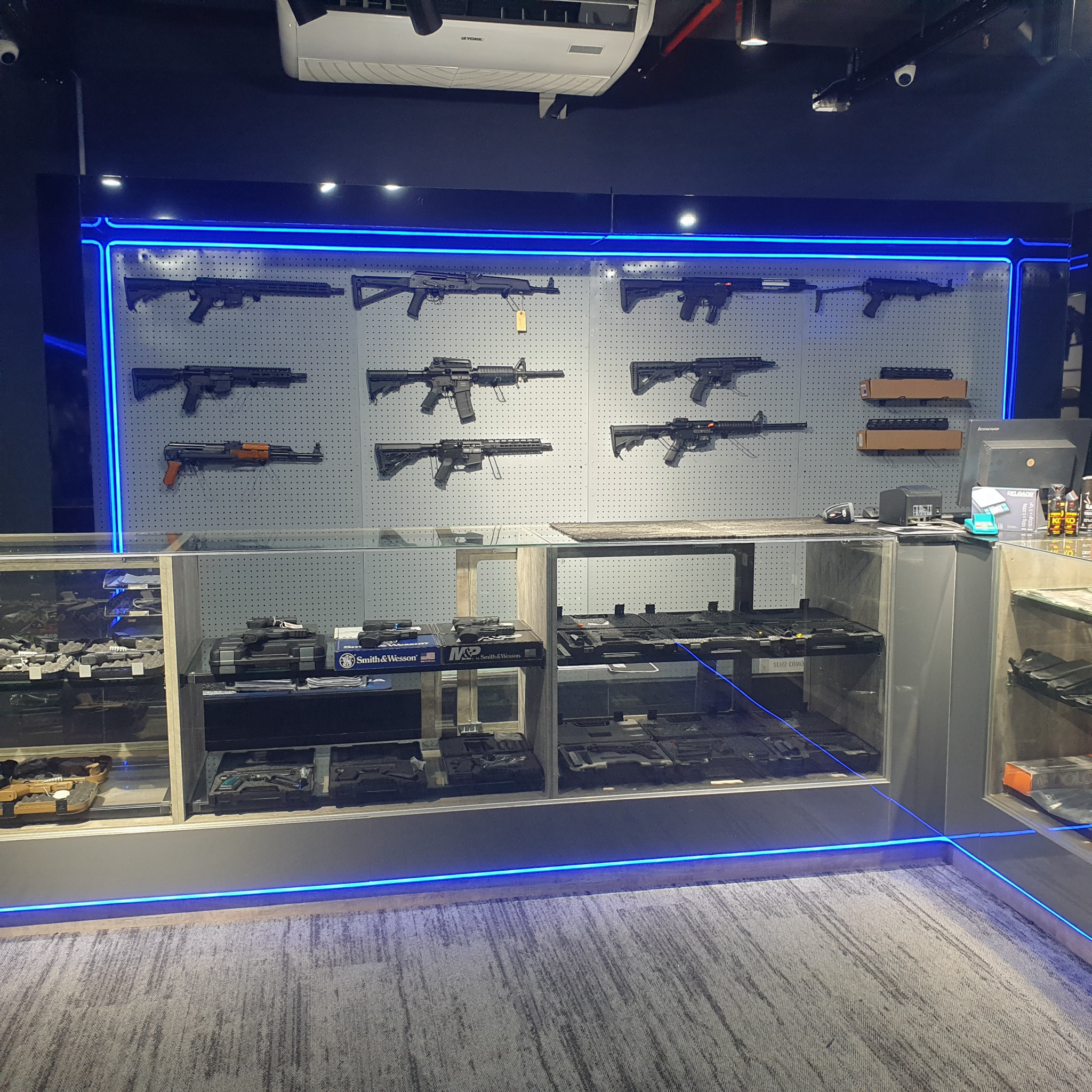 Full sales floor with the rifle display wall, glass counters and the shop counter corner